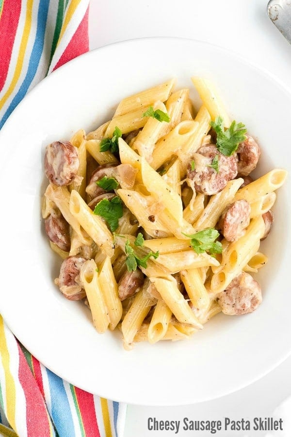 Bowl of Cheesy Sausage Pasta with shallot cream sauce and striped napkin