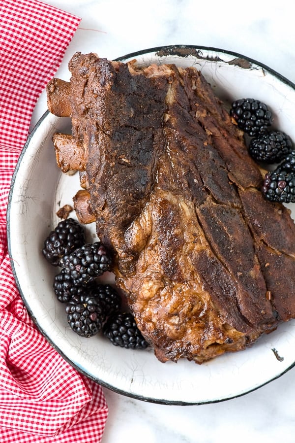 beautiful rack of Baby Back Ribs made in a slow cooker, surrounded by fresh blackberries