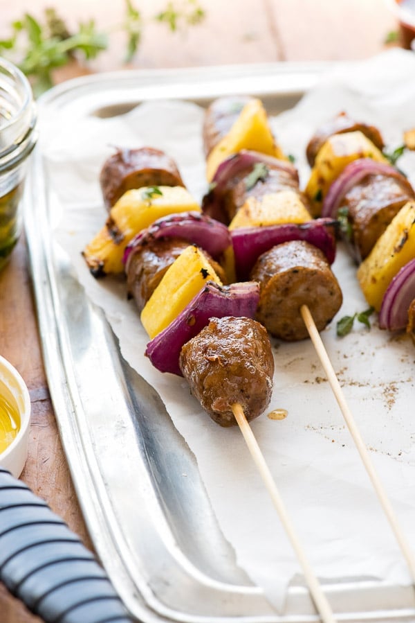 A tray of food on a plate, with Skewer and Sausage