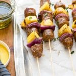 Grilled Cheesy Sausage Pineapple Skewers with individual barbecue sauce for dipping
