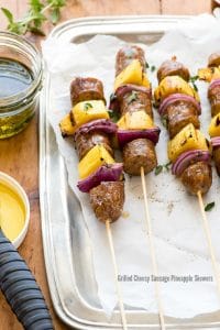 Grilled Cheesy Sausage Pineapple Skewers with individual barbecue sauce for dipping