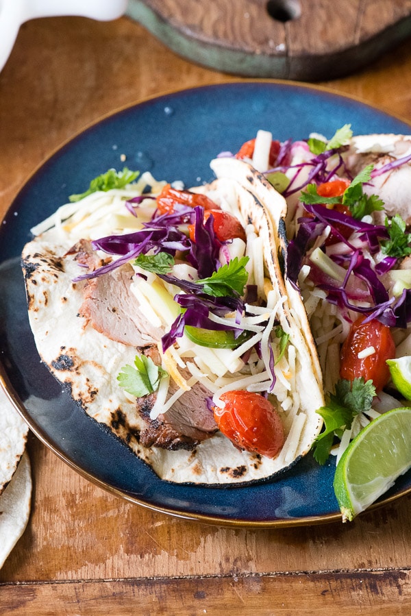 Grilled Pork Street Tacos with Pickled Broccoli Stem Slaw and Blistered Tomatoes On a blue plate