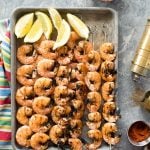 Grilled Spicy Salt and Pepper Shrimp Skewers on a baking sheet with lemon wedges