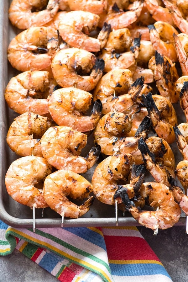 Grilled Spicy Salt and Pepper Shrimp Skewers on a baking sheet with striped towel