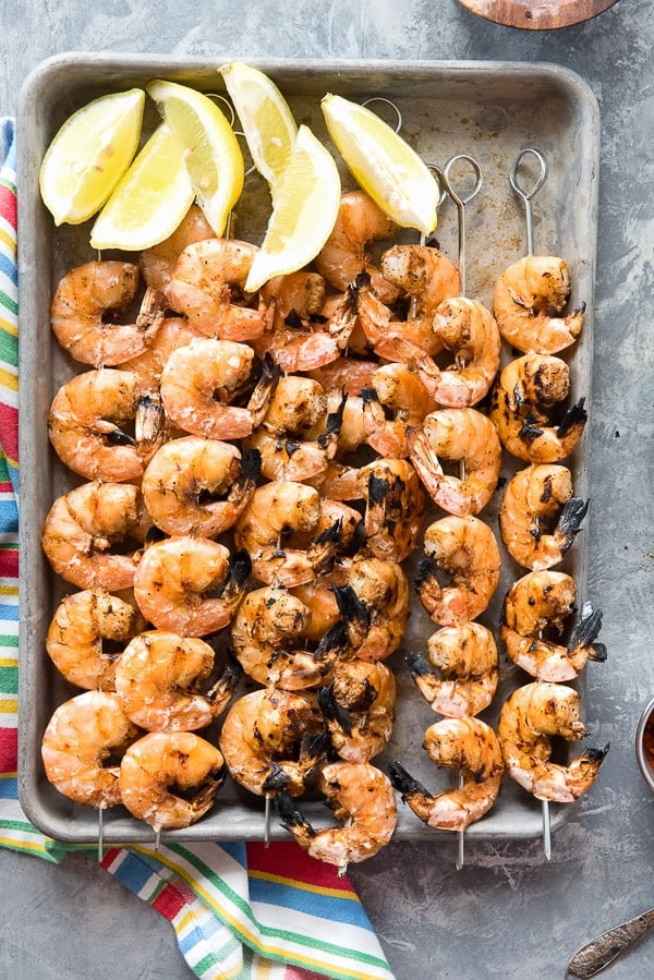 Grilled Spicy Salt and Pepper Shrimp Skewers with lemon wedges on baking sheet