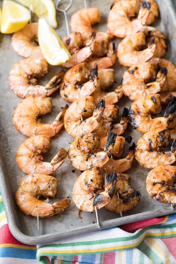 Grilled Spicy Salt and Pepper Shrimp Skewers with lemon wedges on a baking sheet