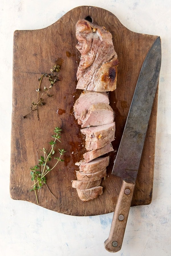 sliced pork tenderloin on wood cutting board