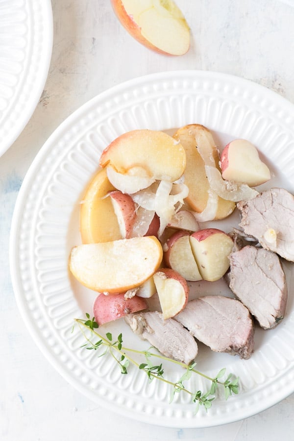 plate of sliced pork tenderloin with apples, onions and potatoes