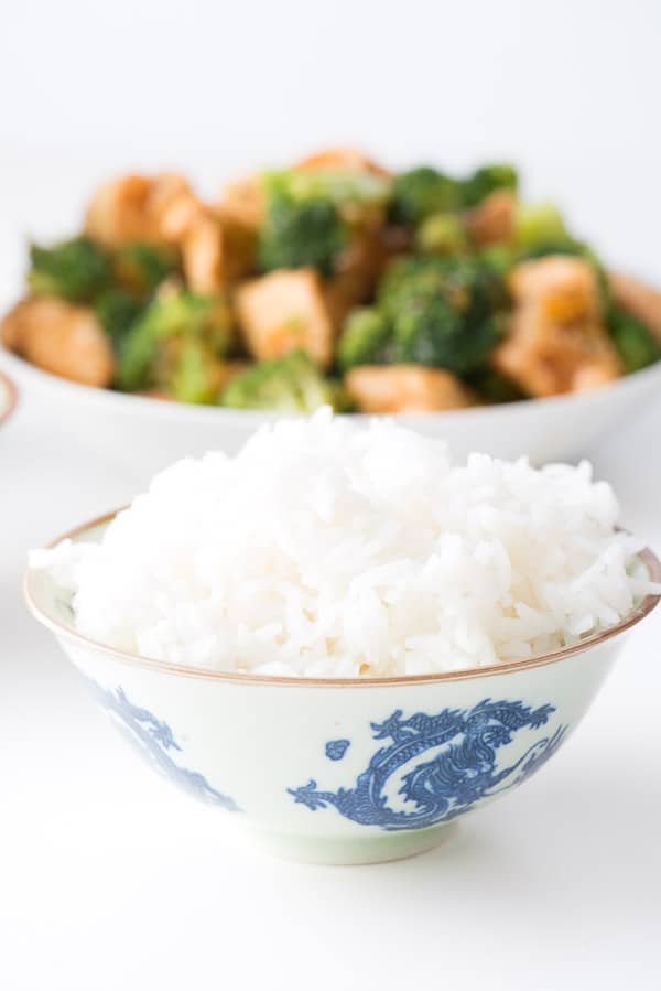 bowl of jasmine rice with Orange Chicken in background