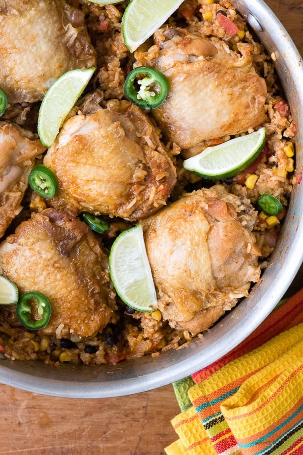 close up photo of Mexican Chicken and Rice Skillet in the skillet with lime wedges