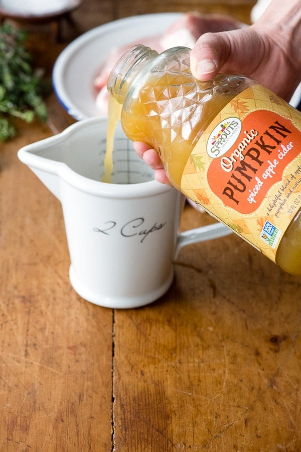 pouring pumpkin spiced apple cider in measuring cup