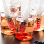 creepy Shirley Temple drinks for Halloween in beakers with syringes