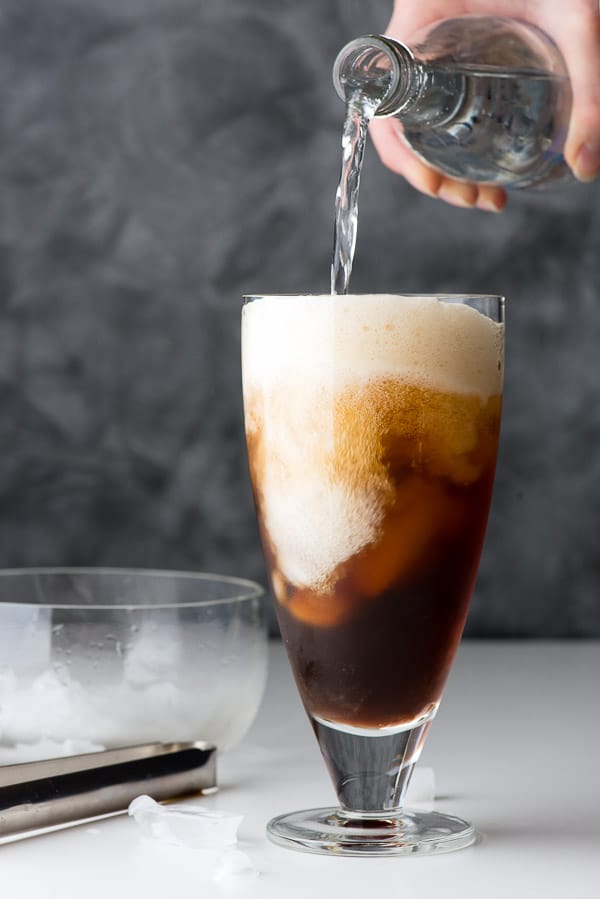 Pouring club soda into a glass of coffee and ice