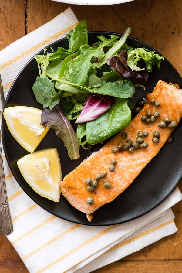 Pan Seared Salmon with capers and salad on a black plate