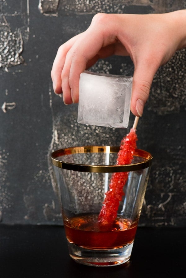 large ice cube being added to cocktail glass