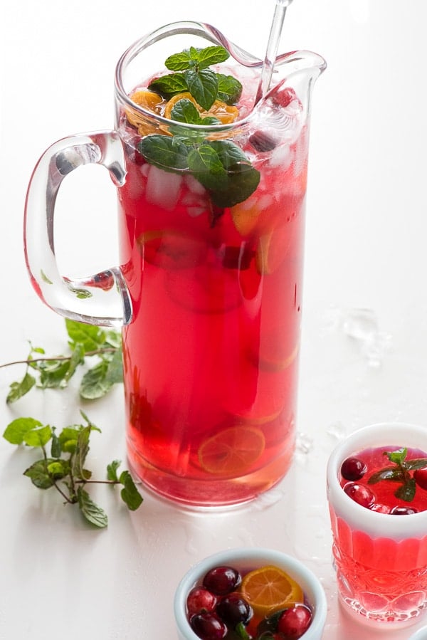 Sparkling Cranberry Vodka Punch with fresh mint in a glass pitcher with a serving glass