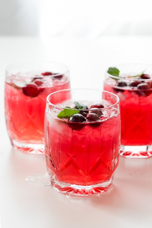 Sparkling Cranberry Vodka Punch in three glasses with fresh cranberries and mint sprigs