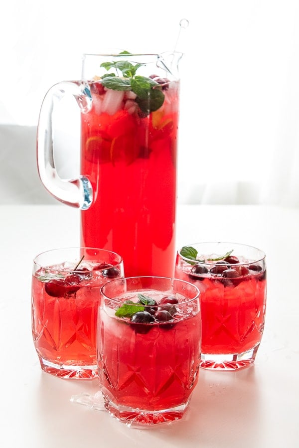 Sparkling Vodka Cranberry Punch in a glass pitcher with three glasses of punch