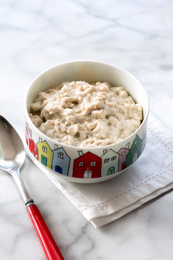 Creamy Overnight Oatmeal Pudding with Cherries in bowl with red spoon