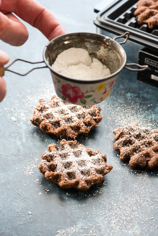 Sprinkling powdered sugar on Double Chocolate Mint Waffle Cookies 