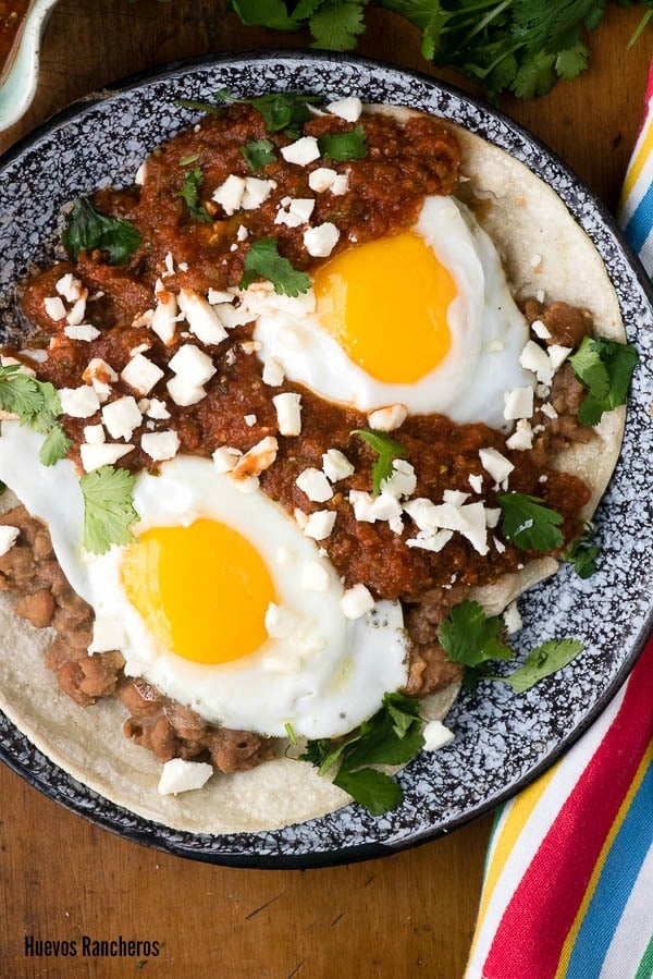 authentic Mexican recipe of Huevos Rancheros on a black speckled plate