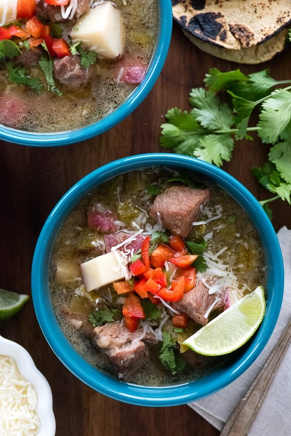 Blue bowl of Green Chile Stew with red pepper