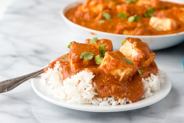 a dinner plate with paneer tikka masala served over fluffy white rice