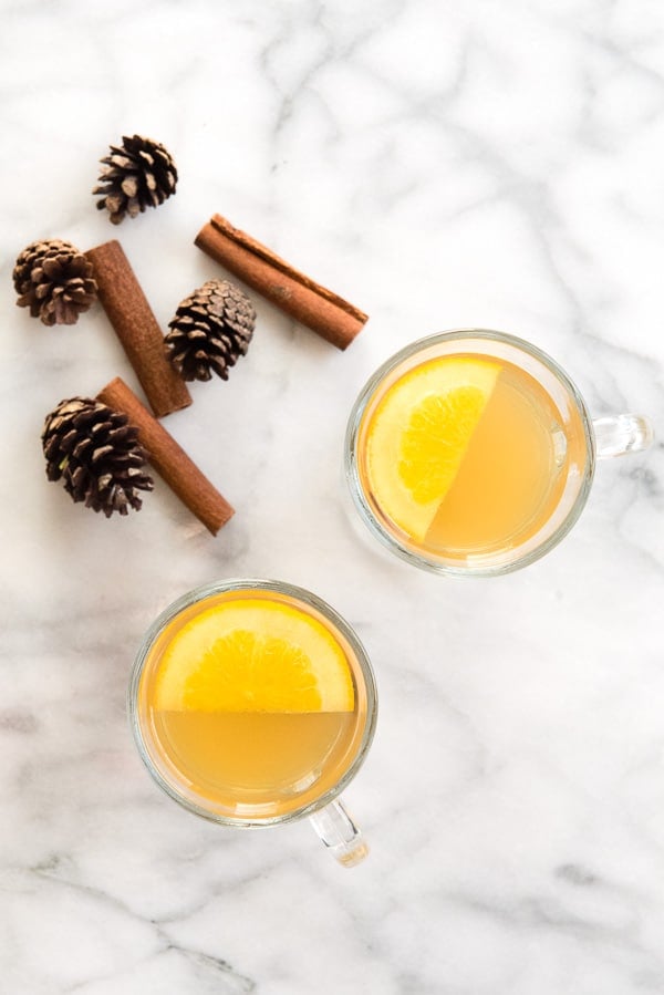 Top view of glass mugs of mulled apple cider with orange slices and cinnamon sticks