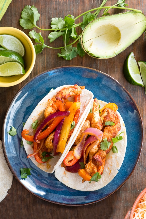 Sheet Pan Chicken Fajitas with avocado, cilantro and lime wedges