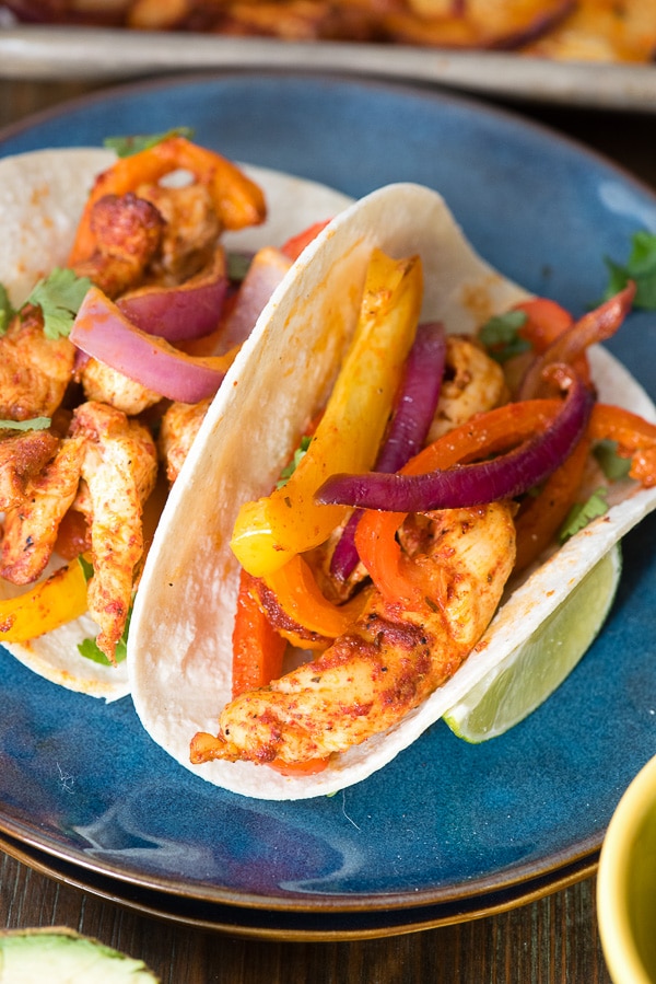 Two prepared chicken fajitas with colorful ingredients on blue plates