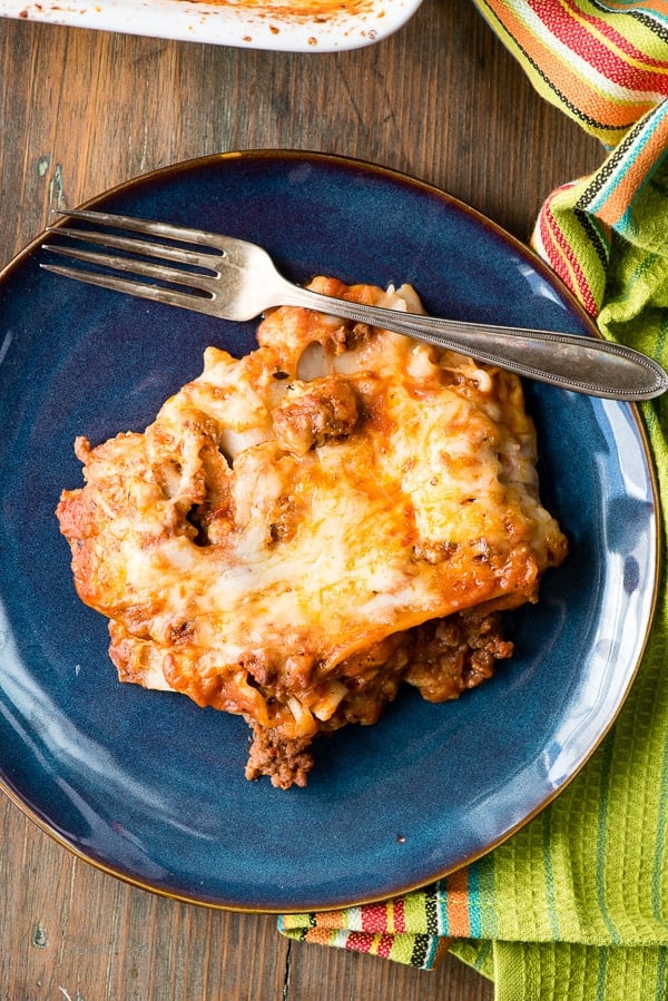 serving of meat and cheese lasagna with gluten-free noodles on blue plate from overhead