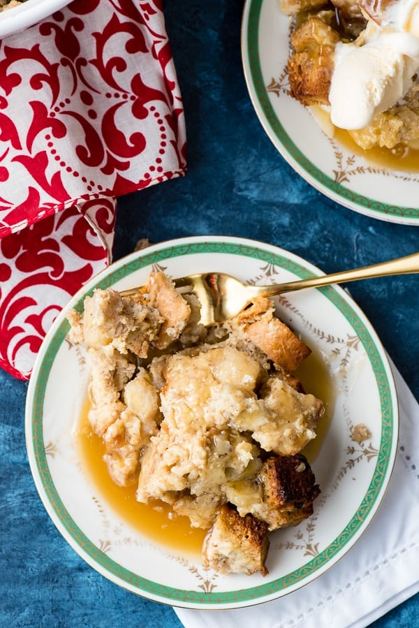 close up of bread pudding with butter rum toffee sauce on plate with fork