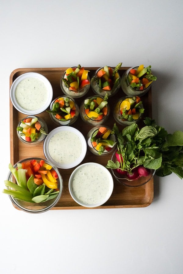 Overhead view of green goddess dressing in bowls and cut vegetables