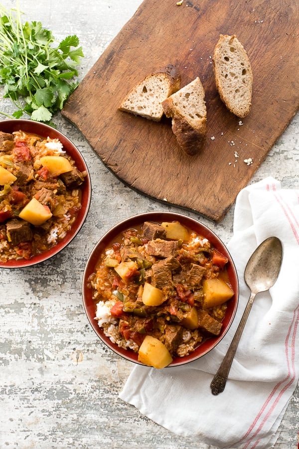 Bowls of Cuban Instant Pot Beef Stew (Carne con Papas) with slices of rustic bread