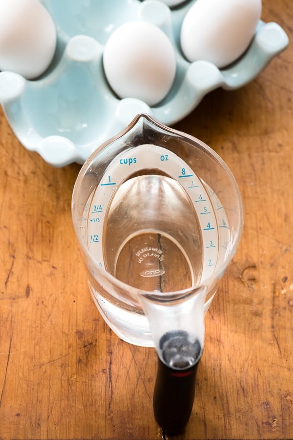 Measuring cup of water with eggs in blue egg container
