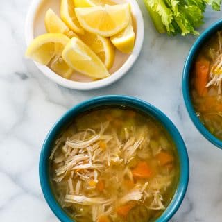 Instant Pot Hearty Chicken Soup in a blue bowl with lemon wedges from above