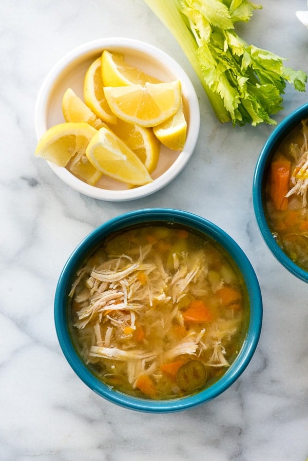 Instant Pot Hearty Chicken Soup in a blue bowl with lemon wedges from above