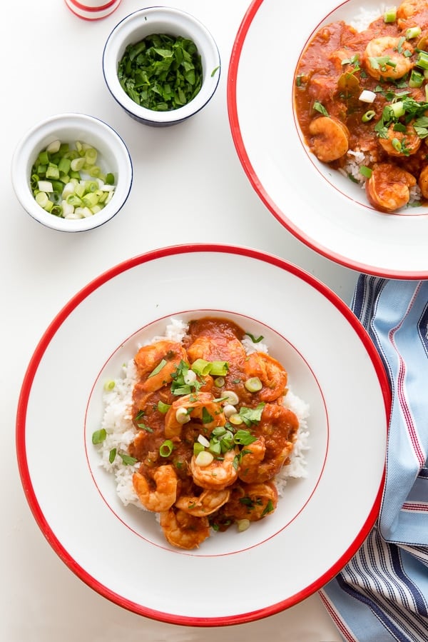 Shrimp Creole over rice in a white bowl with red rim