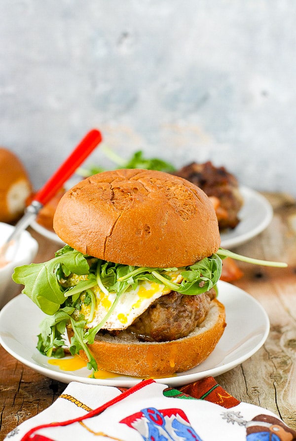 Hot, juicy Bacon-and-Egg Cheese Breakfast Burger with arugula on a white plate 