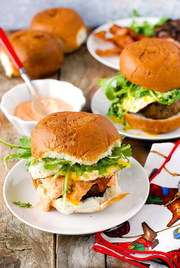 Bacon and Egg Cheese Breakfast Burgers with sriracha sour cream on a white plates 