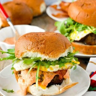 Juicy, grilled Bacon and Egg Cheese Breakfast Burger with arugula on a white plate