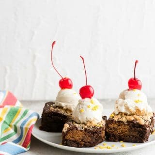 Freshly baked Chocolate Chip Cookie Stuffed Brownies with a scoop of vanilla ice cream and cherries