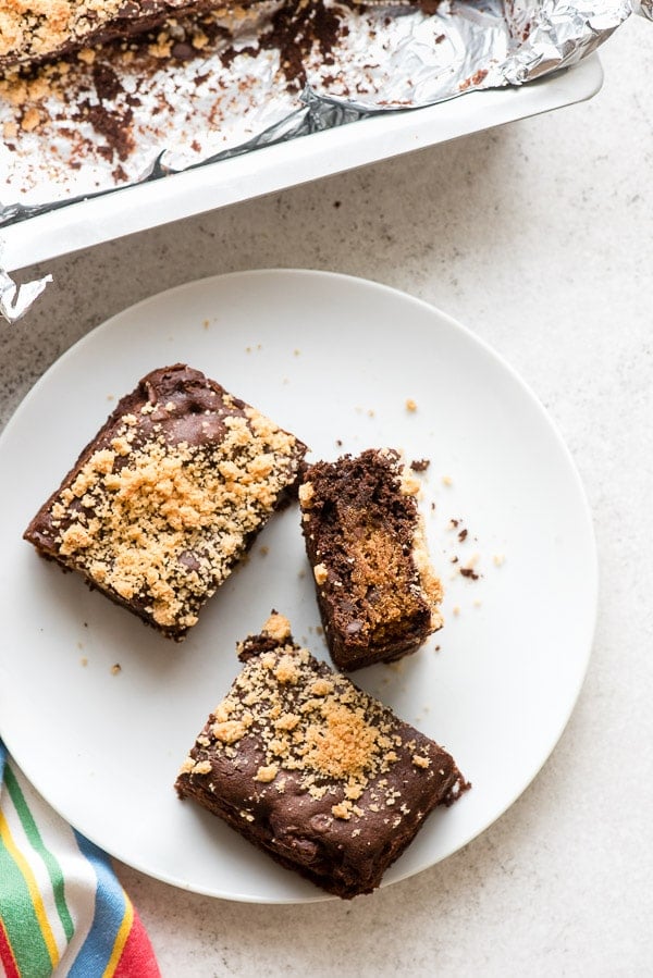 Three fudgy chocolate gluten-free Chocolate Chip Cookie Stuffed Brownies on a white plate 