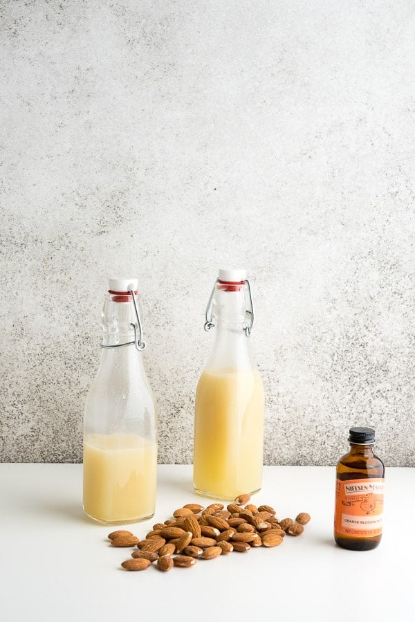 Homemade orgeat syrup in vintage bottles with almonds and orange blossom water