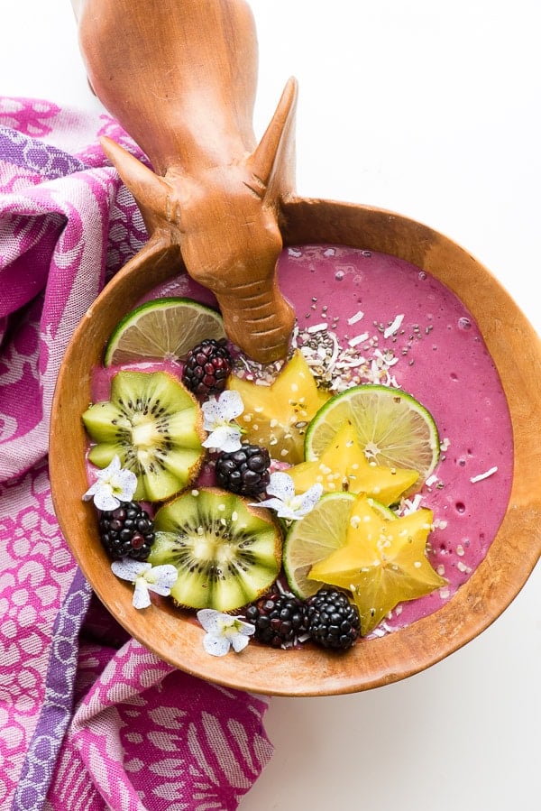Thick, healthy Tropical Bliss Smoothie Bowl with fresh blackberries, star fruit, kiwi, lime slices, shredded coconut
