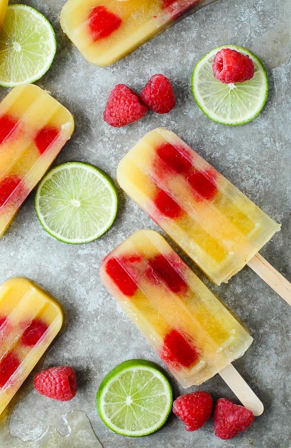 Super refreshing Coconut Water Pineapple Popsicles in vintage mold shape with raspberries and lime slices