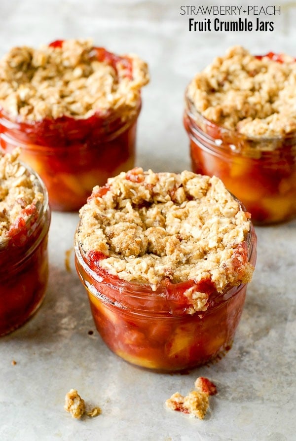 Freshly baked strawberry and peach Fruit Crumble Jars on metal surface 