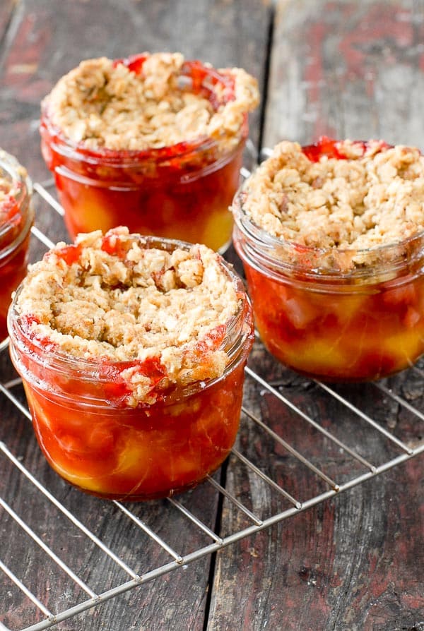 Baked Strawberry Peach Fruit Crumble Jars on metal cooling rack and distressed wood