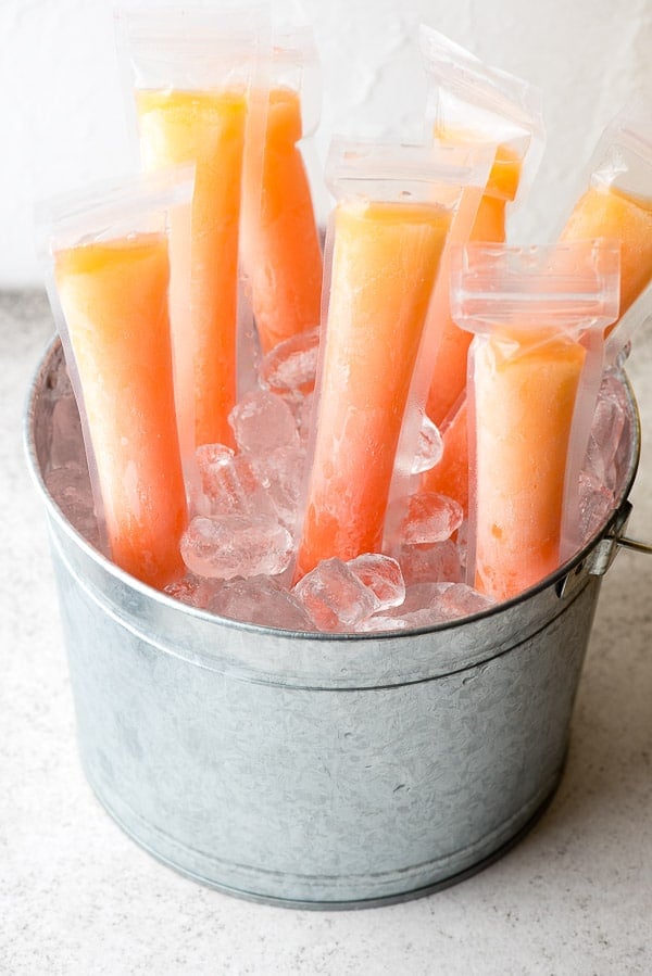 Orange and pink frozen Tequila Sunrise Freezer Pops for adults in a silver galvanized bucket