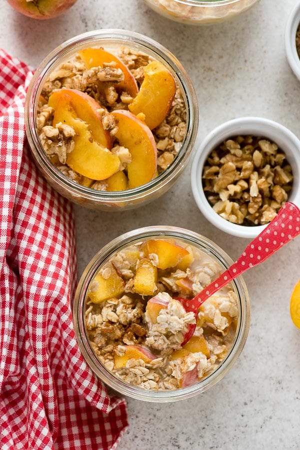 Individual servings of Peach Pie Overnight Oats topped with peach slices, chopped walnuts